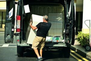 A man is loading up a cabinet from the truck